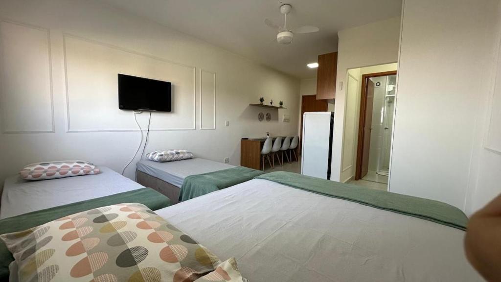 ein Zimmer mit zwei Betten und einem Fernseher an der Wand in der Unterkunft Morada da Fé I 300 m da Canção Nova Cond Da fé in Cachoeira Paulista
