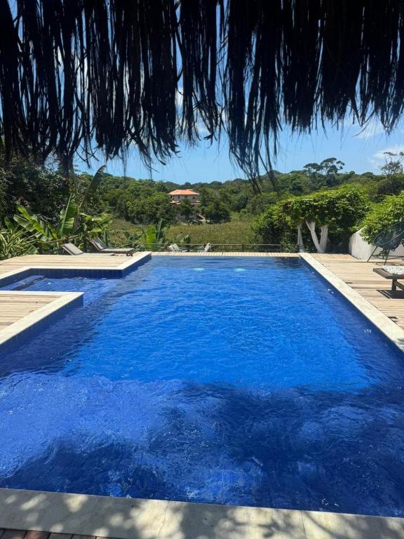 a blue swimming pool with a view of a house at Recanto do Villa 3 in Trancoso