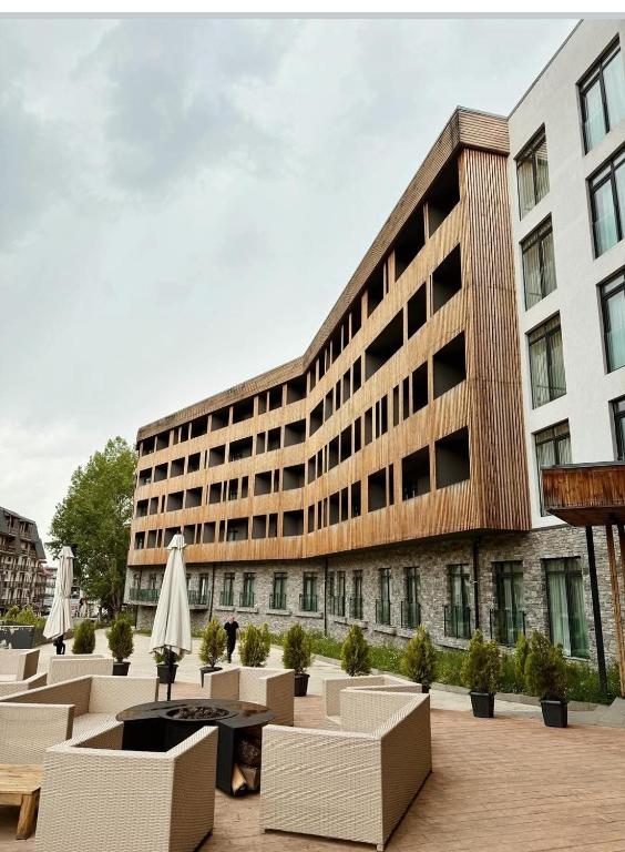 a large building with chairs and a table and umbrella at Arkhi Kokhta Bakuriani Apt 304 in Bakuriani