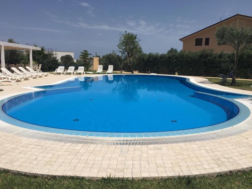a large blue swimming pool with chairs in a yard at Villa dell'Ulivo - by DomuSicily in Terrasini