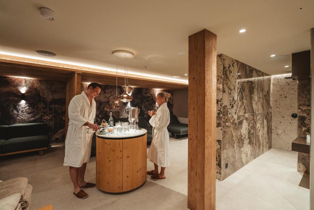 a man and woman in white robes standing at a bar at Matterhorn Inn - Wellness & Dining - at Zermatt Shuttle Station in Täsch