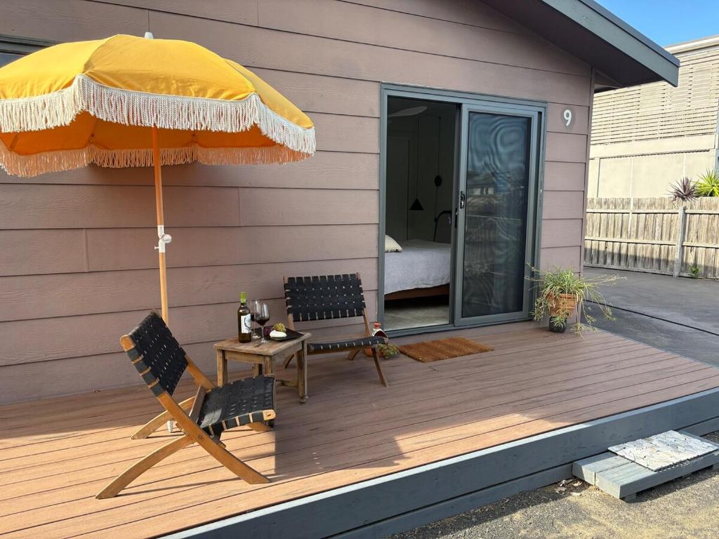 a wooden deck with two chairs and an umbrella at Guest suite in Phillip Island in Cape Woolamai
