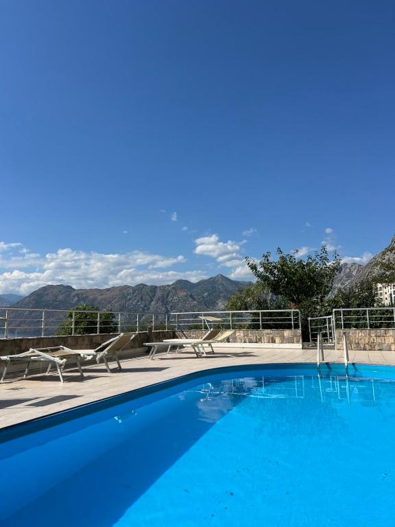 a blue swimming pool with chairs and mountains in the background at Maya bay in Kotor