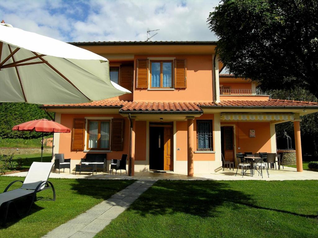 a house with a table and chairs and an umbrella at Villa in Tuscany with pool in Loro Ciuffenna