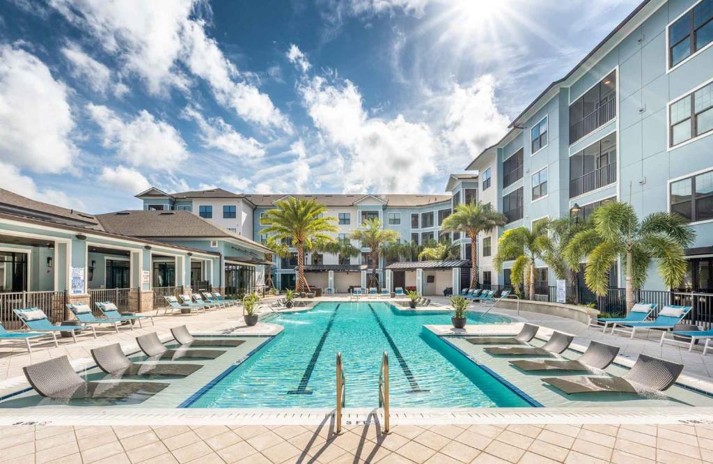 a pool at a hotel with chairs and palm trees at Monarch Apartments 15m to Parks, Pet Friendly, Free Parking by Heavenly Homes in Orlando