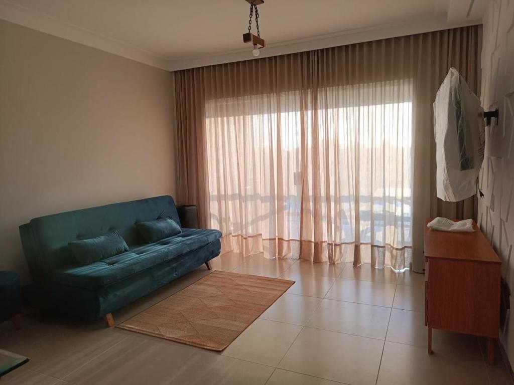 a living room with a green couch and a large window at Refúgio com Lazer de Resort in Estância
