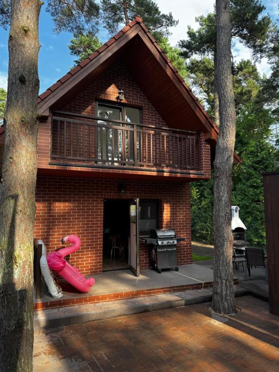 une maison en briques rouges avec un balcon et une aire de jeux dans l'établissement Ceglana Przystań - Apartamenty i Domek Pogorzelica, à Pogorzelica