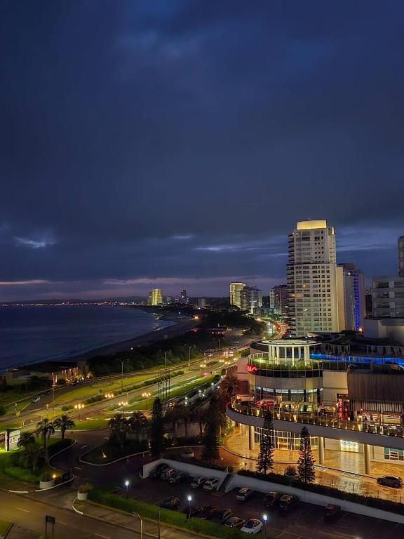 a city skyline at night with the ocean and buildings at Alexander Beach Punta del Este in Punta del Este