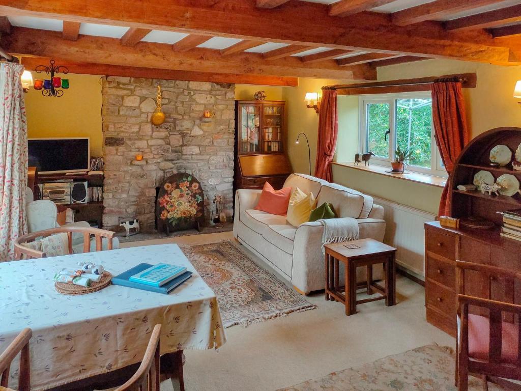 a living room with a couch and a table and a fireplace at Cow Cottage in Langford
