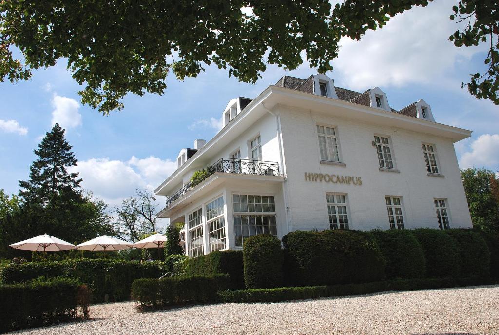 un grand bâtiment blanc avec des buissons devant lui dans l'établissement Hotel Hippocampus, à Mol