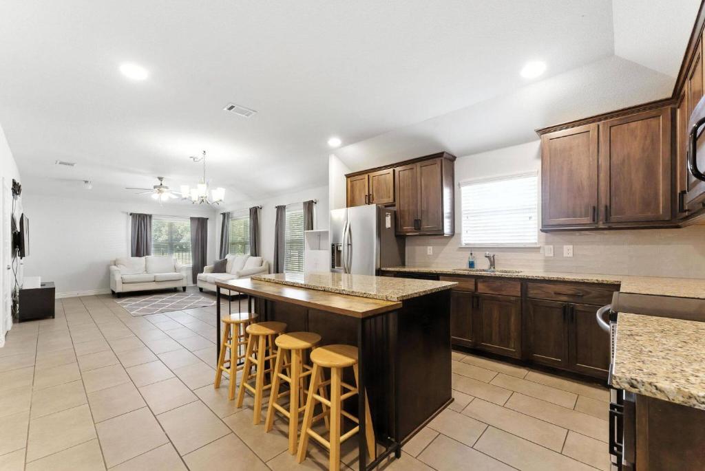 a kitchen with wooden cabinets and a kitchen island with bar stools at Luxury Home Mins to JPS & Medical City Fort Worth in Fort Worth