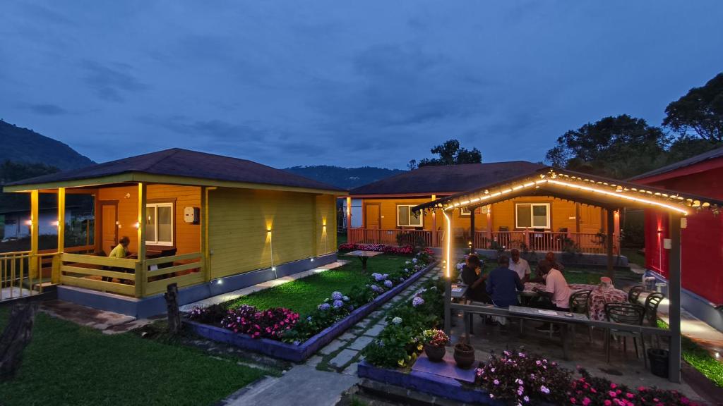 a house with people sitting at a table in the yard at The Laughing Woods AC Resort in Kotagiri