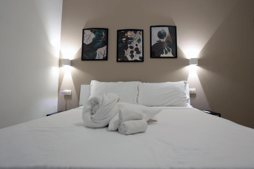 a bedroom with a white bed with three pictures on the wall at Casa Noal - a due passi da Ortigia e dal mare in Syracuse