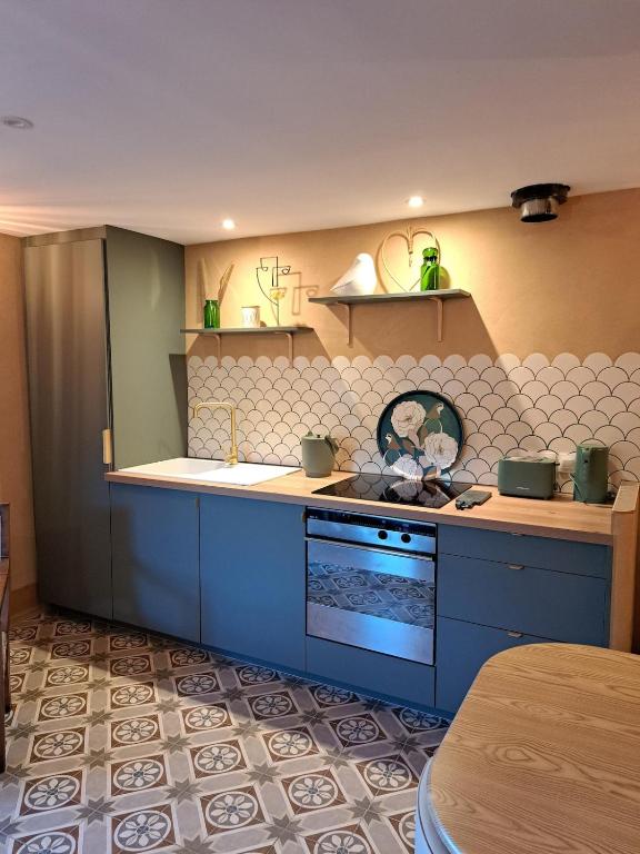 a kitchen with blue cabinets and a stove top oven at Écolieu La Bernarde - Gîte Nature in Dompnac