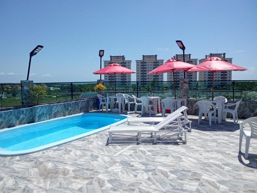 ein Pool mit Stühlen, Tischen und Sonnenschirmen in der Unterkunft Hotel Torre do Sal in Salinópolis