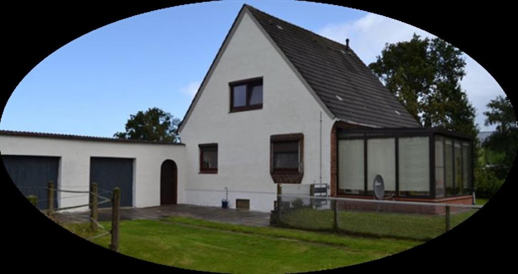 a large white house with a black roof at Ferienhaus am Nordostseekanal in Offenbüttel