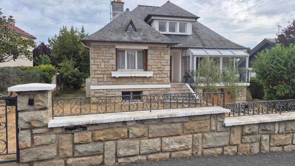 a house with a stone retaining wall and a fence at Grande maison avec jardin a proximité centre ville in Laval
