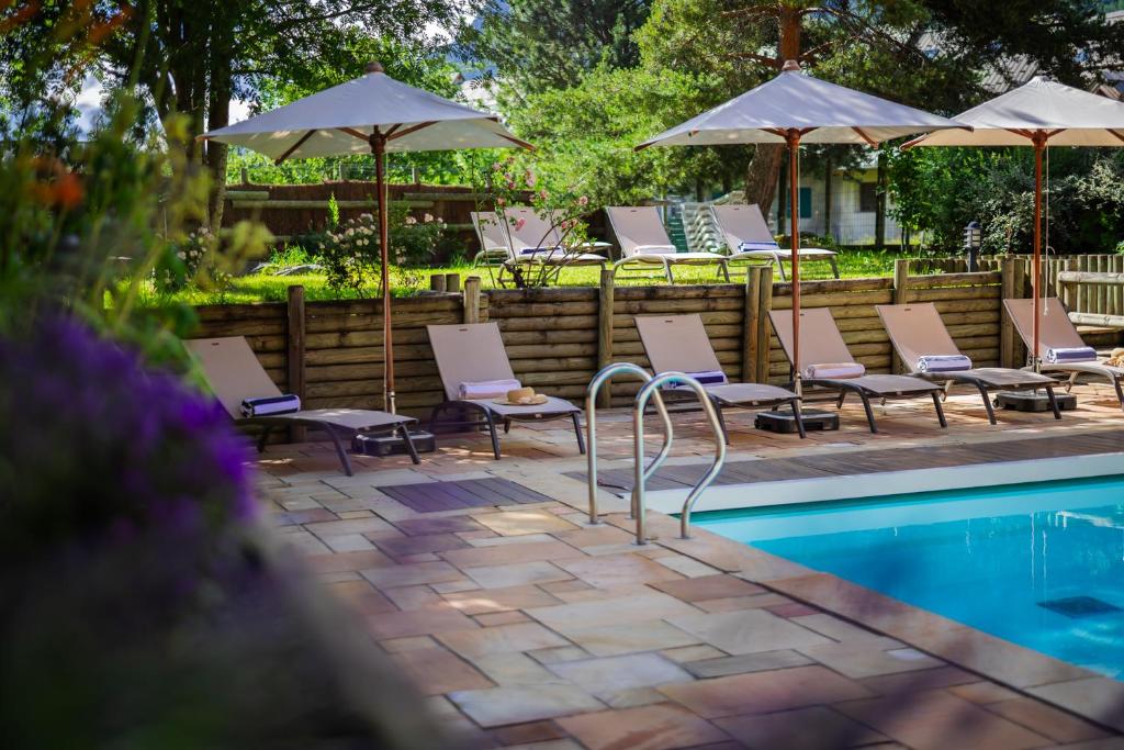 a group of chairs and umbrellas next to a pool at Alliey & Spa Piscine Appart-hôtel Serre chevalier in Le Monêtier-les-Bains