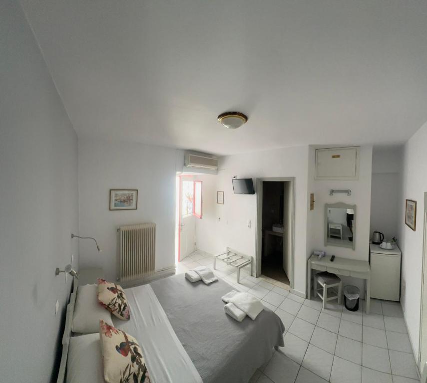 a white room with a bed and a desk at BAHIA Guest House in Hydra