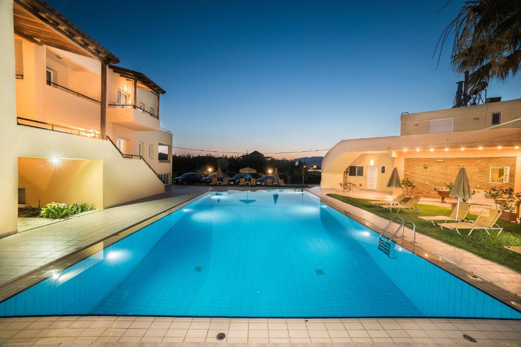 uma piscina em frente a um edifício à noite em Mythos Beach Hotel Apartments em Máleme
