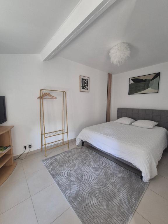 a white bedroom with a bed and a rug at La longère du Moulin in Basse-Goulaine