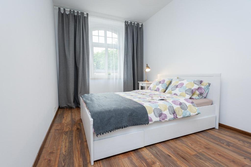 a bedroom with a white bed and a window at Apartment Zamulkowa Katowice in Katowice