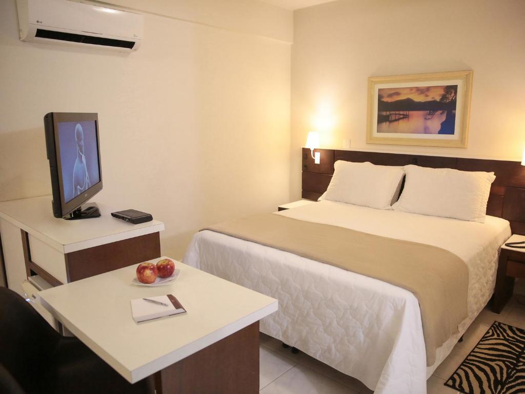 a hotel room with a bed and a tv at Altadomo Hotel in Santa Maria