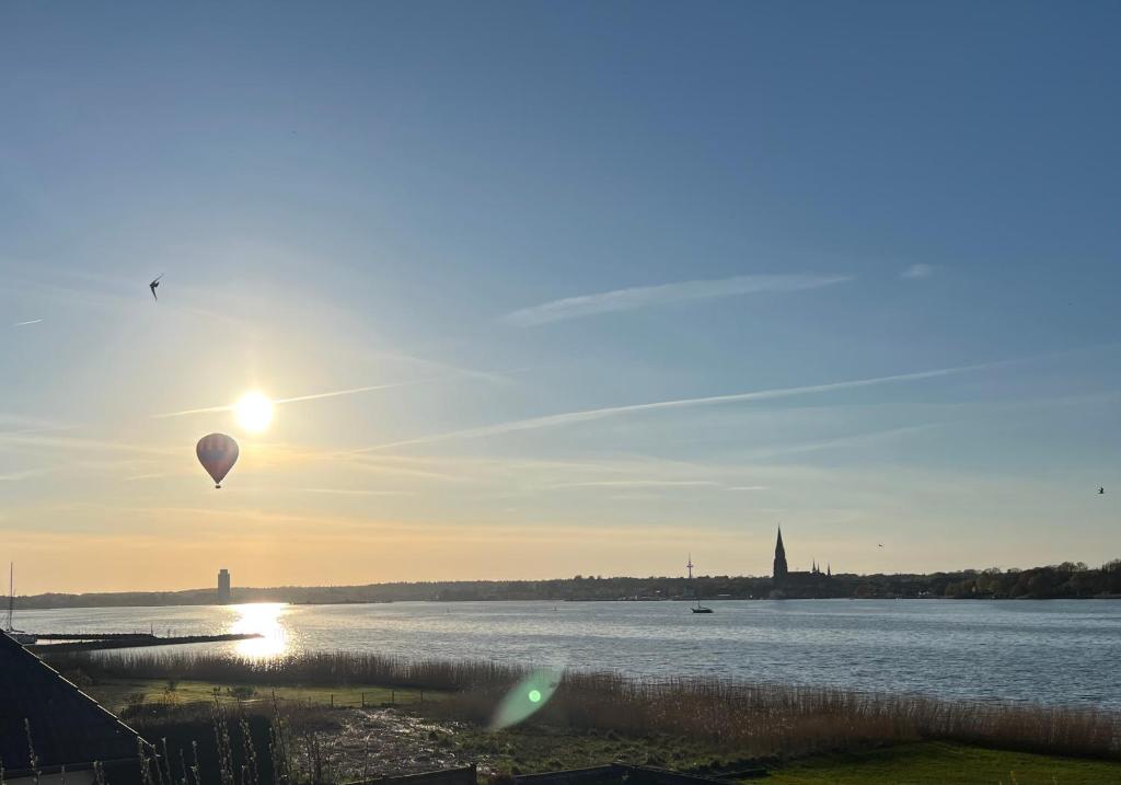 a hot air balloon flying over a body of water at Lichtdurchflutete Ferienwohnung mit direktem Schleiblick in Fahrdorf