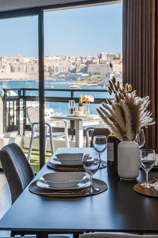 a table with plates and wine glasses on a balcony at Top Location-2BR Seafront & Steps from Ferry by Arco Collection in Sliema