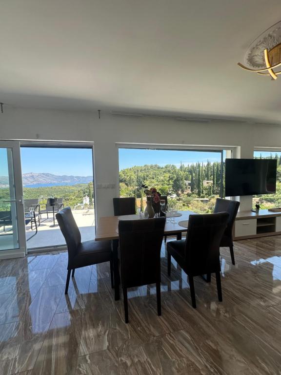 a dining room with a table and chairs and large windows at Appartement Ellara Penthouse in Žrnovo