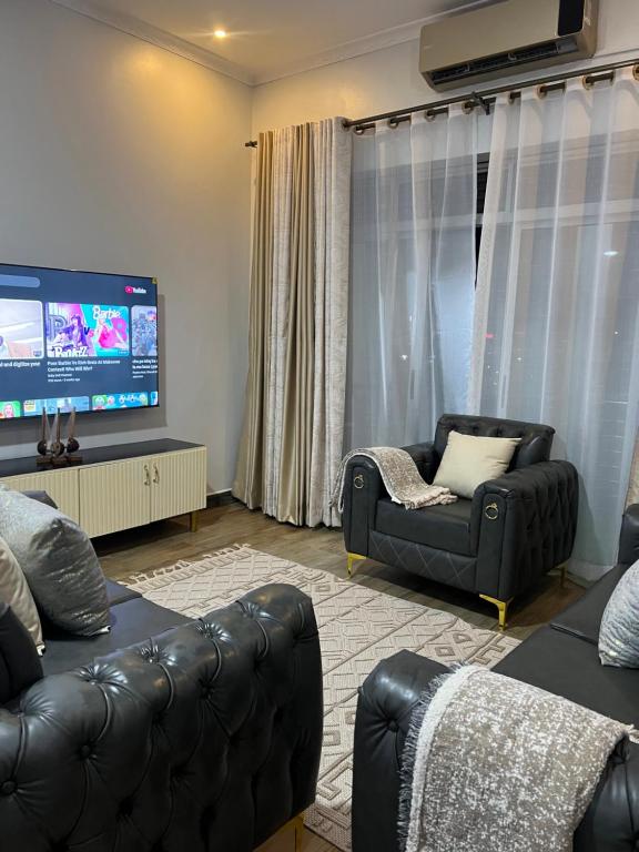a living room with black leather furniture and a flat screen tv at HA LUXURY 3BEDROOM LAKEVIEW munyonyo in Kampala