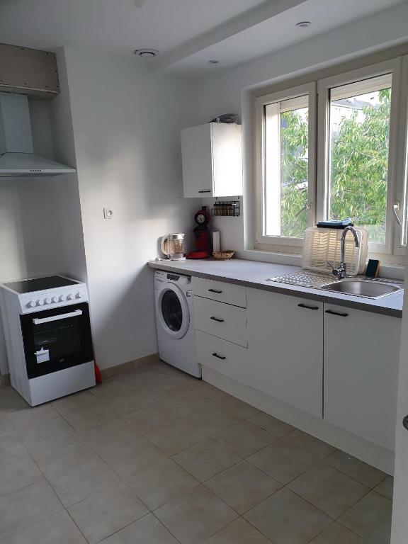 a white kitchen with a sink and a washing machine at appartement avec beau jardin in Blois