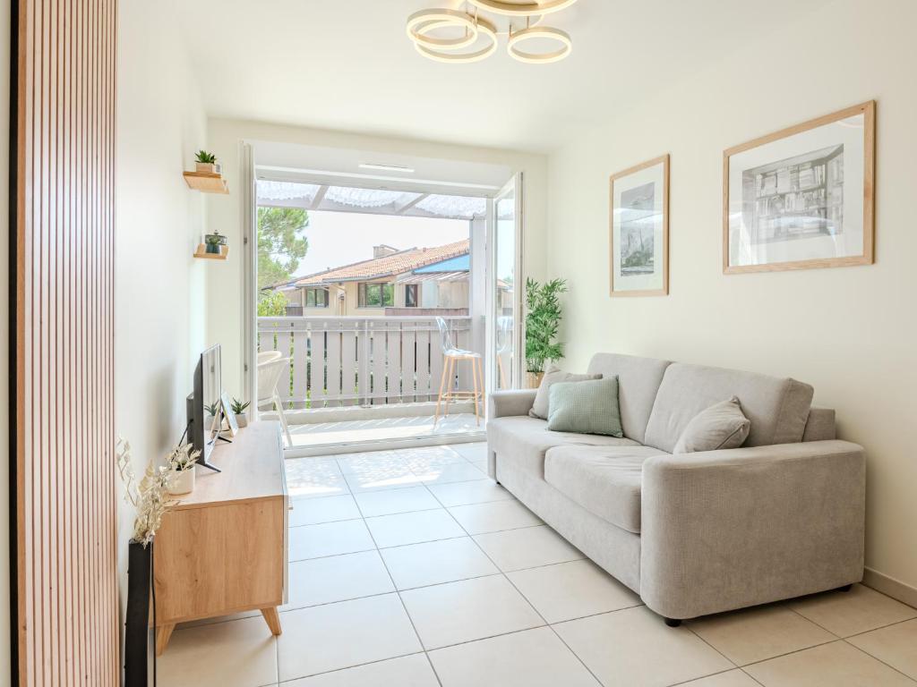 a living room with a couch and a tv at L'appartement près de la source in Mimizan-Plage