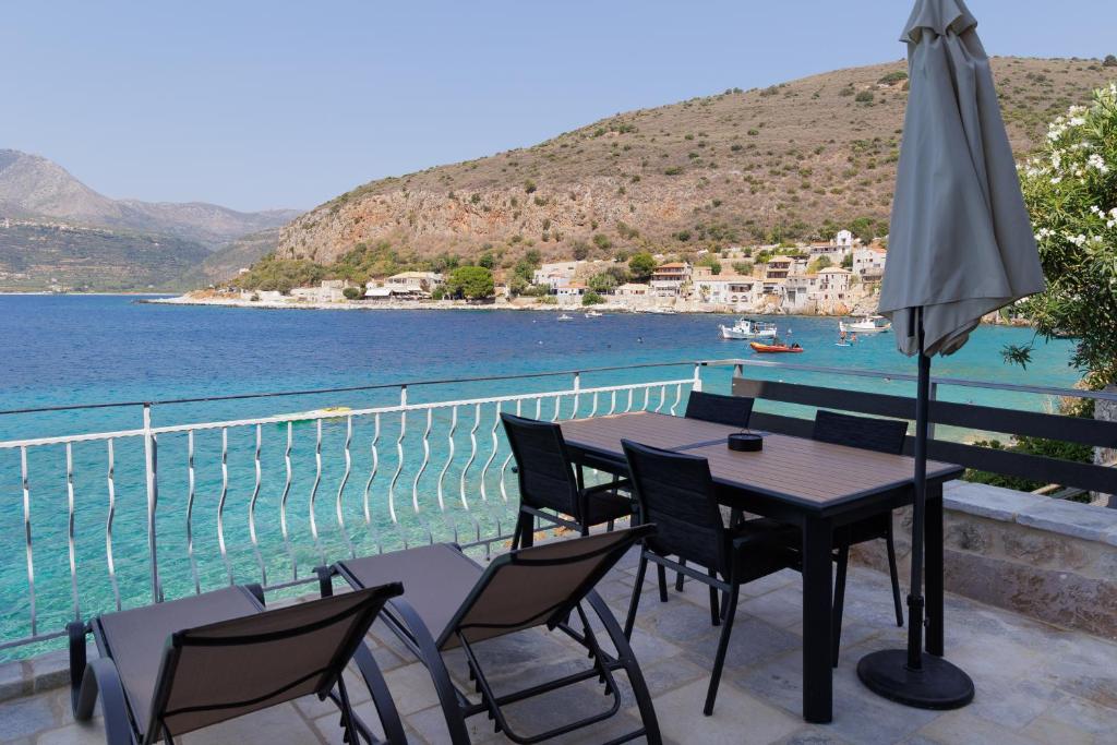 a table with chairs and an umbrella on a balcony at Limeni koilakos Suite in Limeni