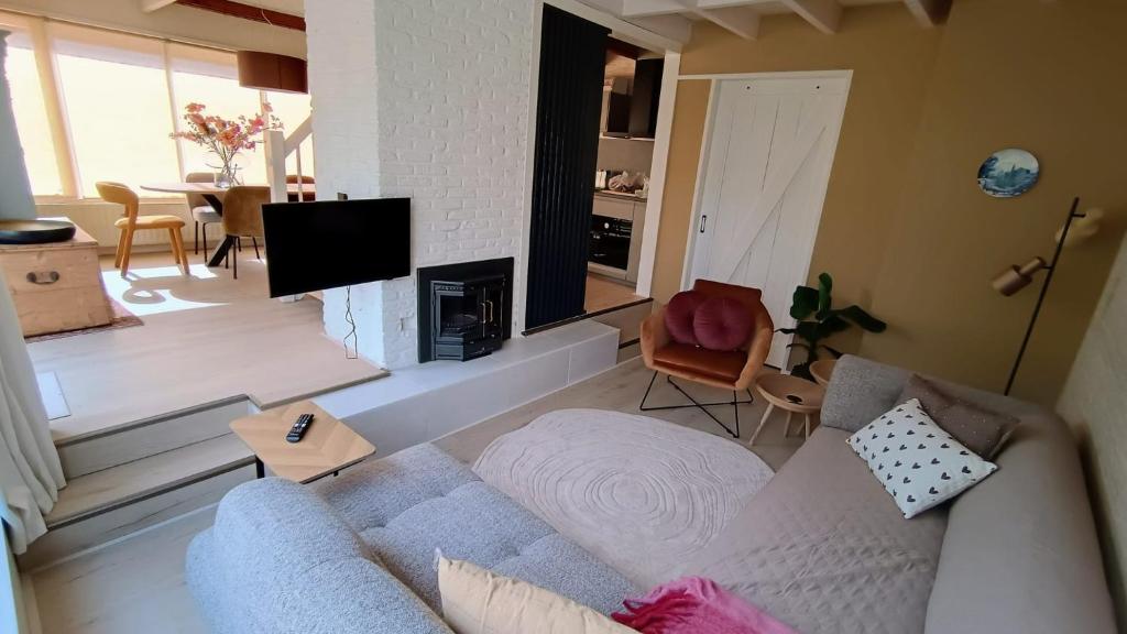 un salon avec un canapé et une télévision dans l'établissement Vakantiehuis Lycka, à Noordwijkerhout
