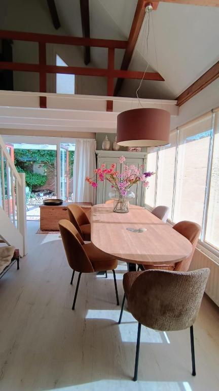 a dining room table with chairs and a vase of flowers at Vakantiehuis Lycka in Noordwijkerhout
