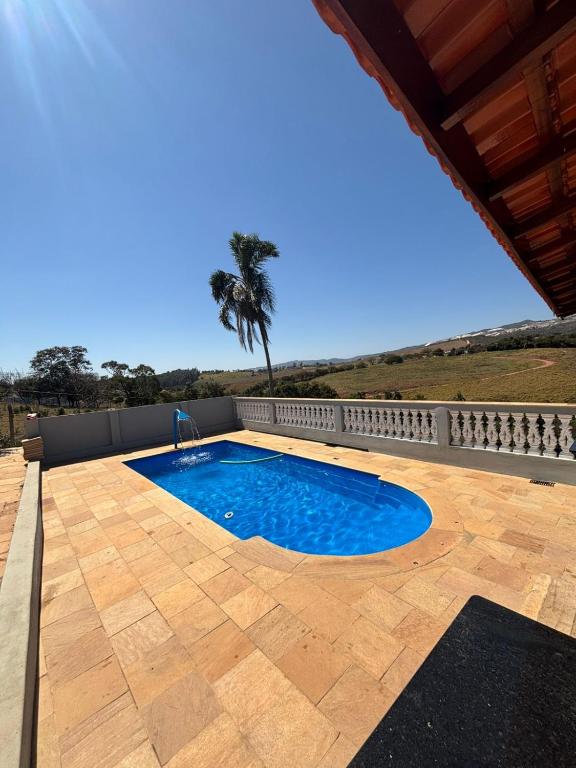 a swimming pool in a patio with a palm tree in the background at Chácara a 2km do centro de São Thomé in São Thomé das Letras