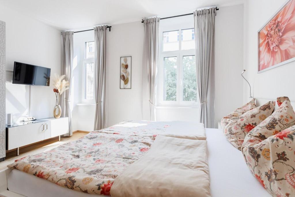 ein weißes Schlafzimmer mit einem Bett und einem Fernseher in der Unterkunft Central Renovated Apartment with AC & Free Parking in Wien