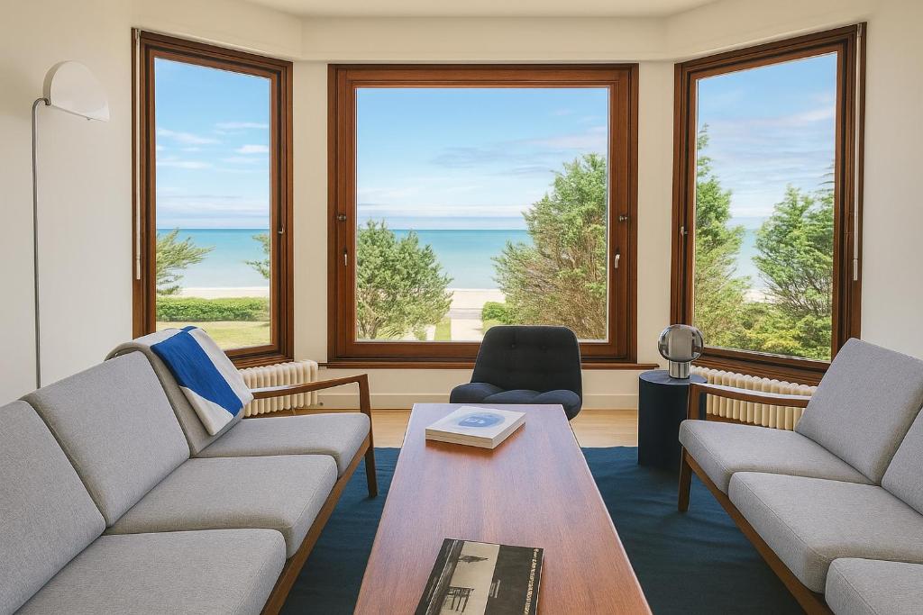 a living room with two couches and a table at La Sauvagère - Villa Art Deco face à Omaha Beach in Vierville-sur-Mer