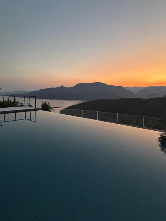 a swimming pool with a sunset in the background at Casa do Beija in Outeiro