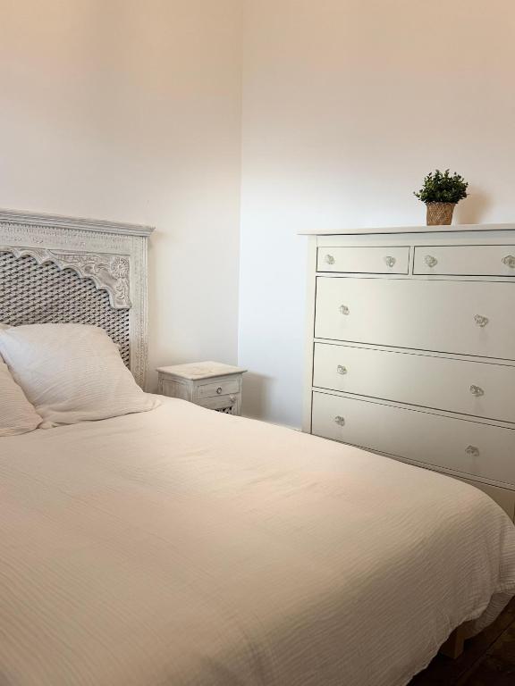 a bedroom with a white bed and a dresser at Argence logement T2 in Angoulême