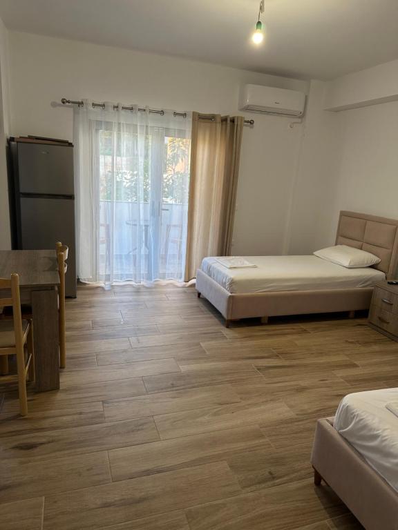 a bedroom with two beds and a table and a window at La casa de Alex in Sarandë