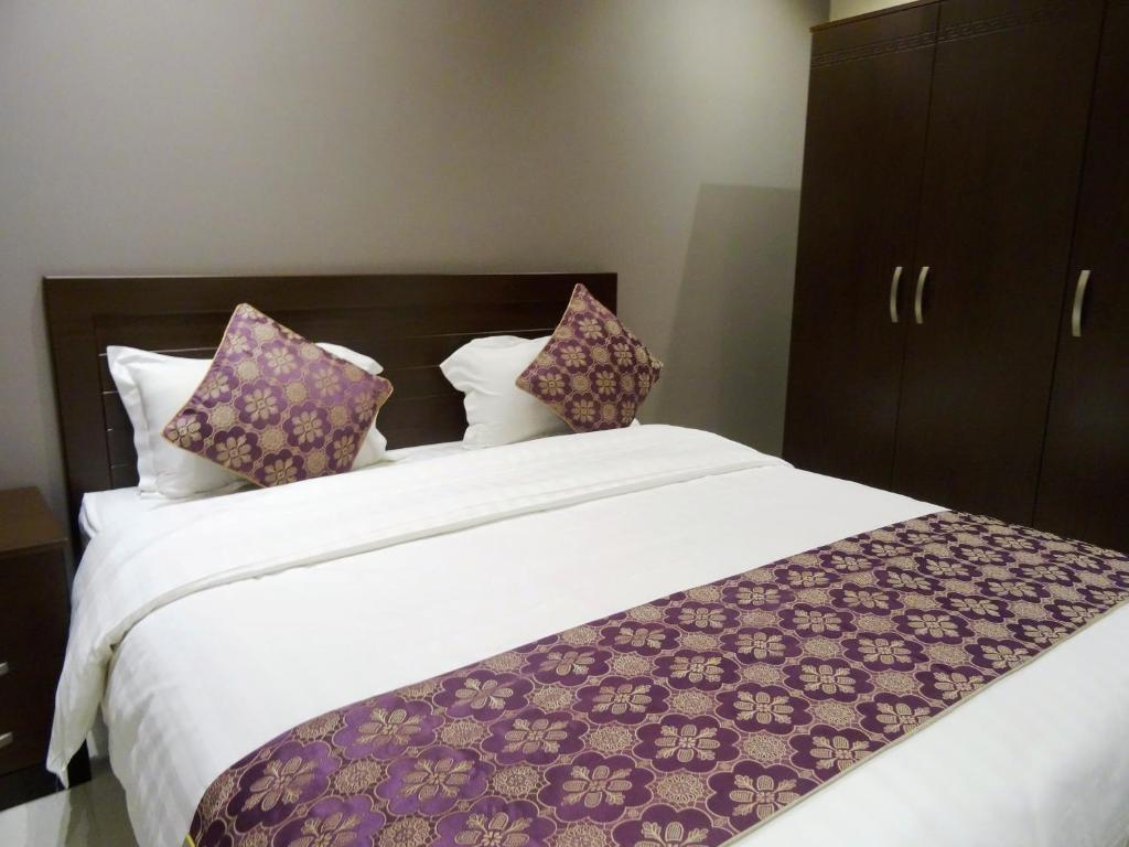 a bedroom with a large bed with purple and white pillows at Dar Hashim Hotel Suites - Al Sahafa in Riyadh