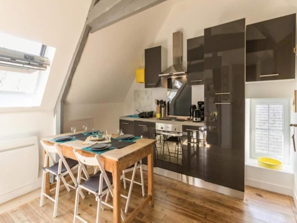 a kitchen with a wooden table and black appliances at Romantic Escape in Normandy in Isigny-sur-Mer