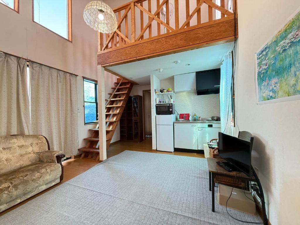 a living room with a couch and a kitchen at Azumi Holiday House in Azumino