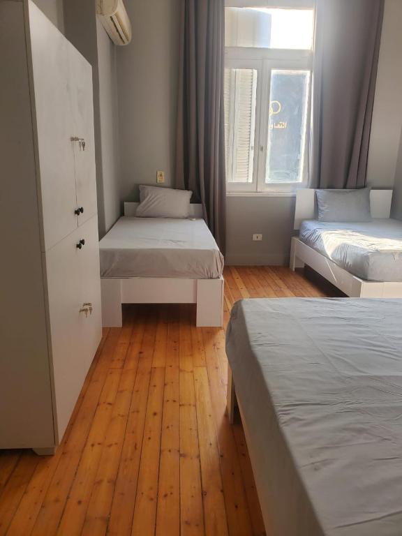 a bedroom with two beds and a wooden floor at nice comfy bedroom in Cairo