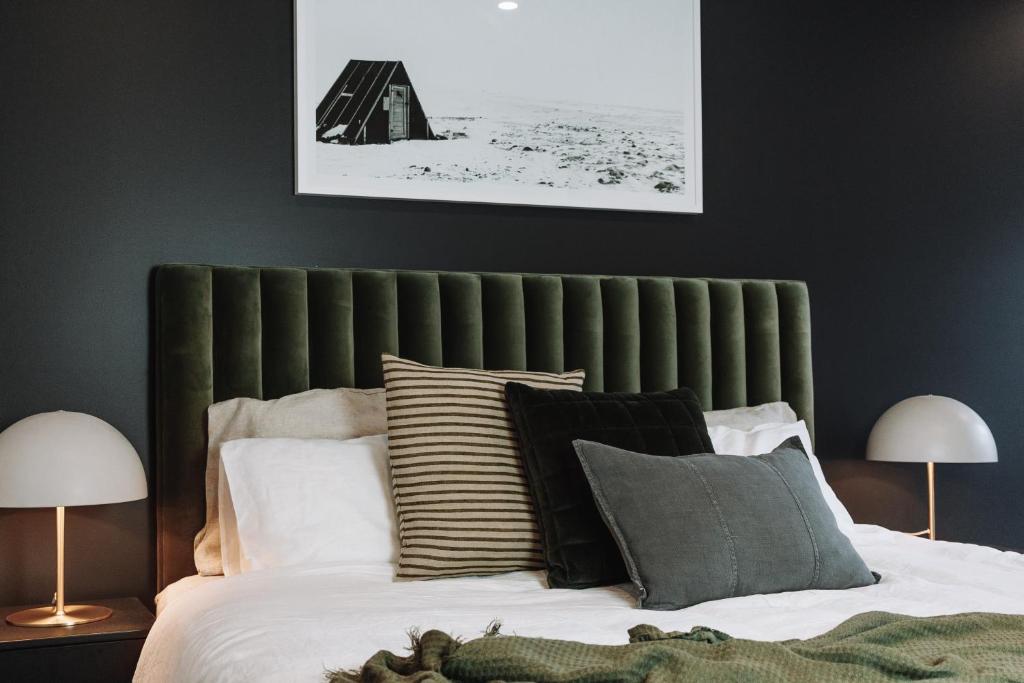 een slaapkamer met een groen hoofdeinde en kussens op een bed bij Hygge East 302 St Falls in Falls Creek