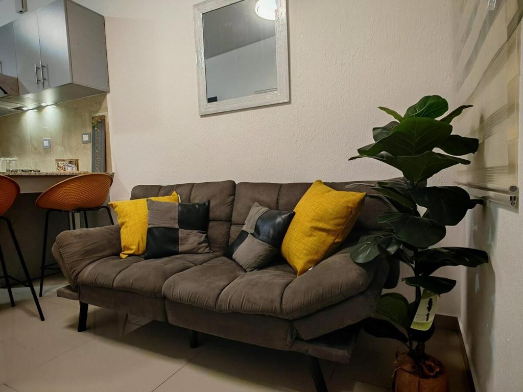 a living room with a brown couch with yellow pillows at Home Style 31 in San Miguel