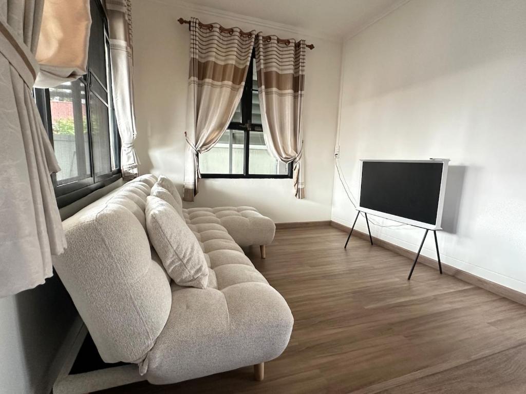 Una sala de estar con un sofá y un televisor de pantalla plana. en 2BR New renovation house in Phitsanulok, en Ban Khlong