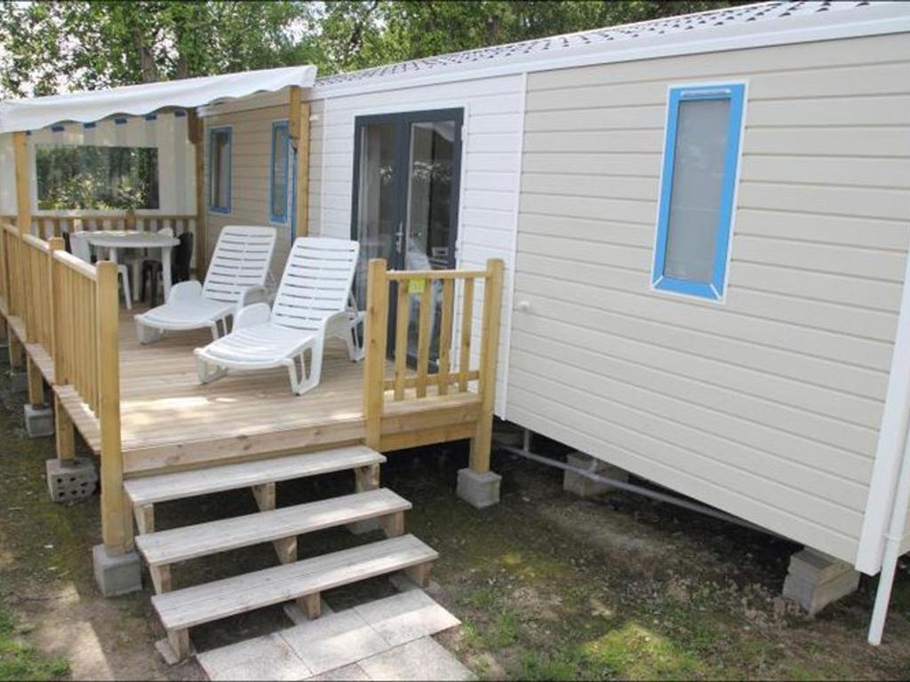 a house with a deck with chairs and a table at Mobil home confortable avec terrasse pour 6 personnes - API-1-52-304 in Brétignolles-sur-Mer